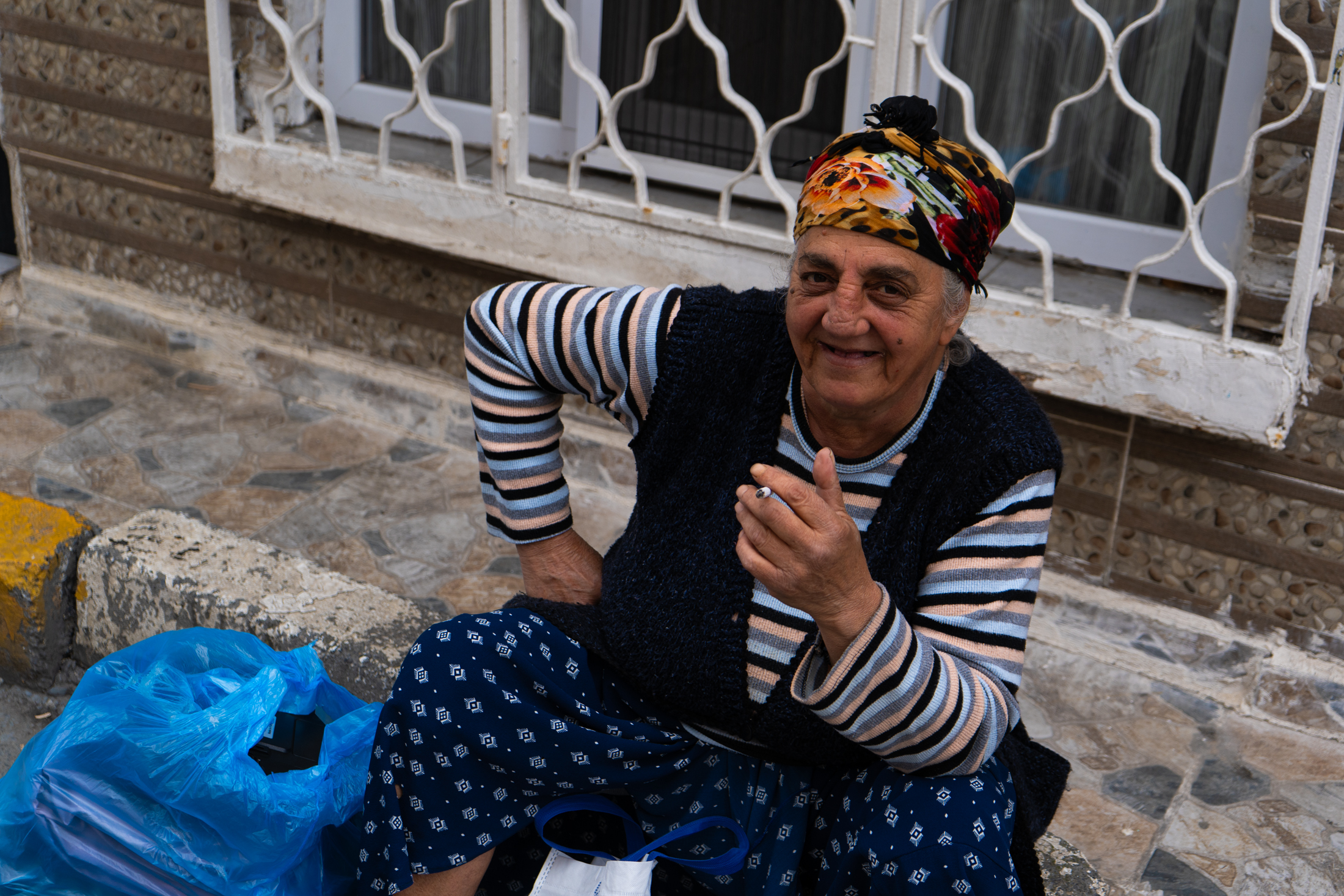 Στην πολυεθνική γειτονιά του Κουρτουλούς, όπου κατοικούν και Έλληνες, μία γυναίκα απολαμβάνει το τσιγάρο στης στο πεζοδρόμιο.